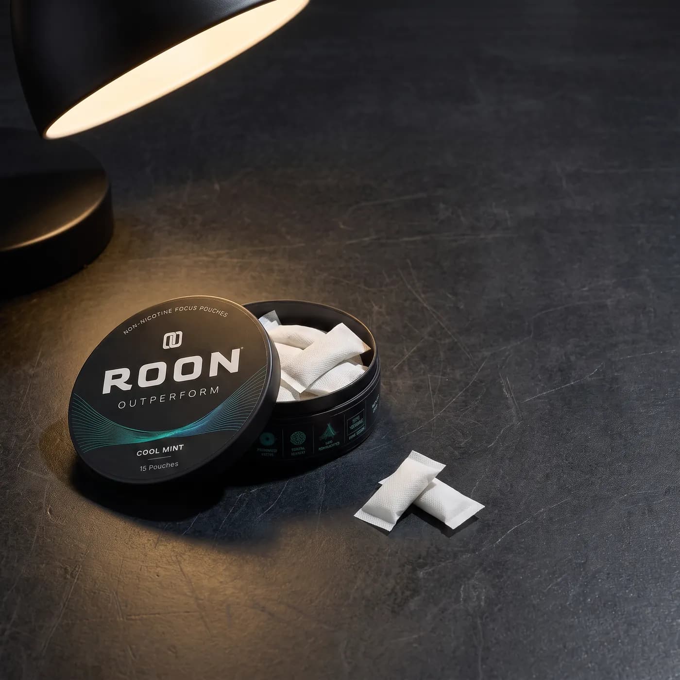 An open tin of Roon Cool Mint pouches on a bright desk beside a closed laptop and a notebook.