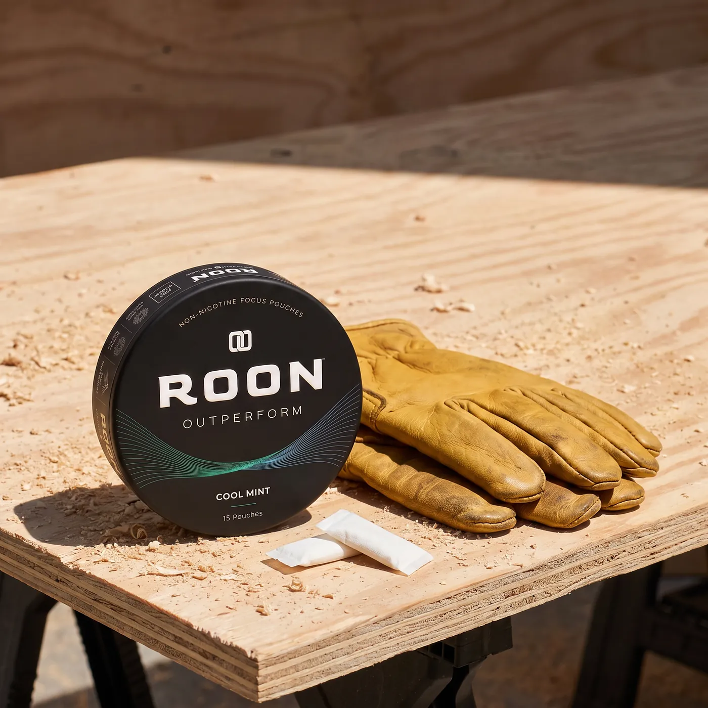 A closed tin of Roon Cool Mint pouches on a workbench beside a folded pair of work gloves.