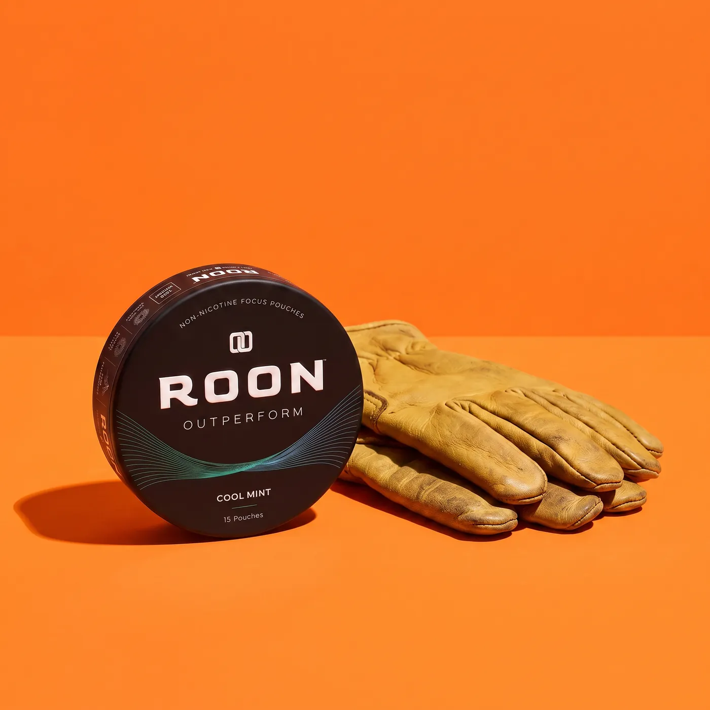 A closed tin of Roon Cool Mint pouches on a workbench beside a folded pair of work gloves.
