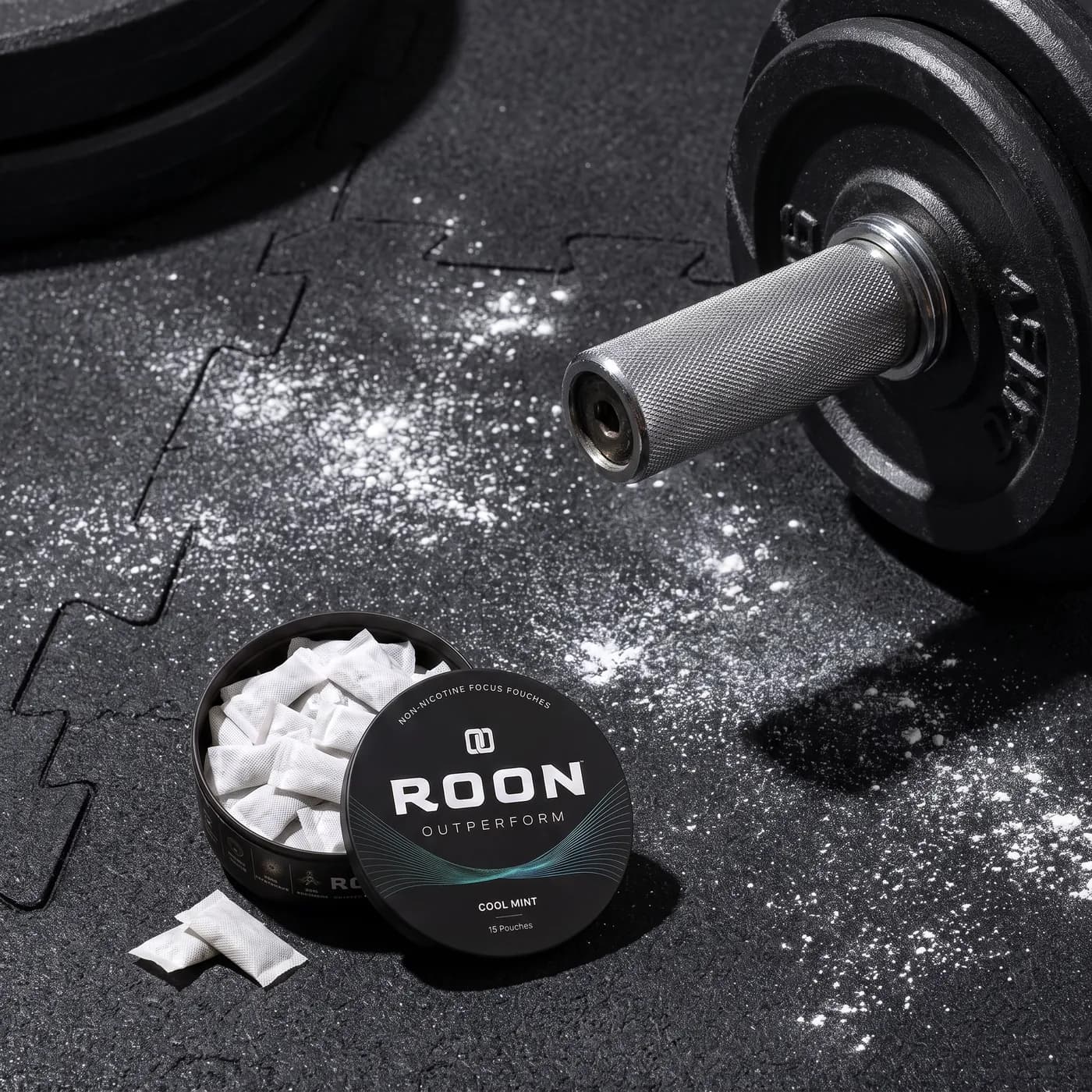 An open tin of Roon Cool Mint pouches on a bench beside a water bottle in a bright gym.