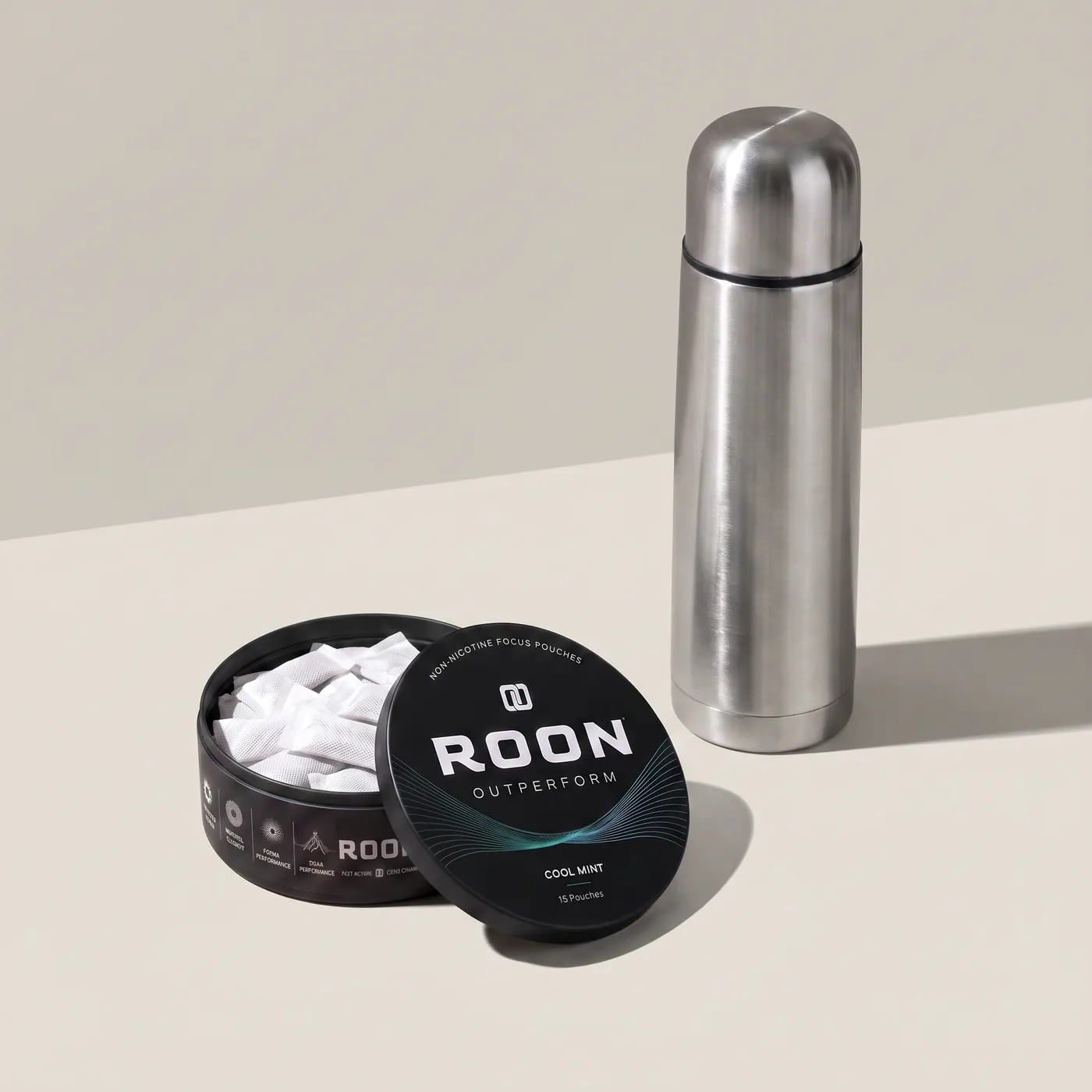 An open tin of Roon Cool Mint pouches on a bright break room counter beside a stainless flask.