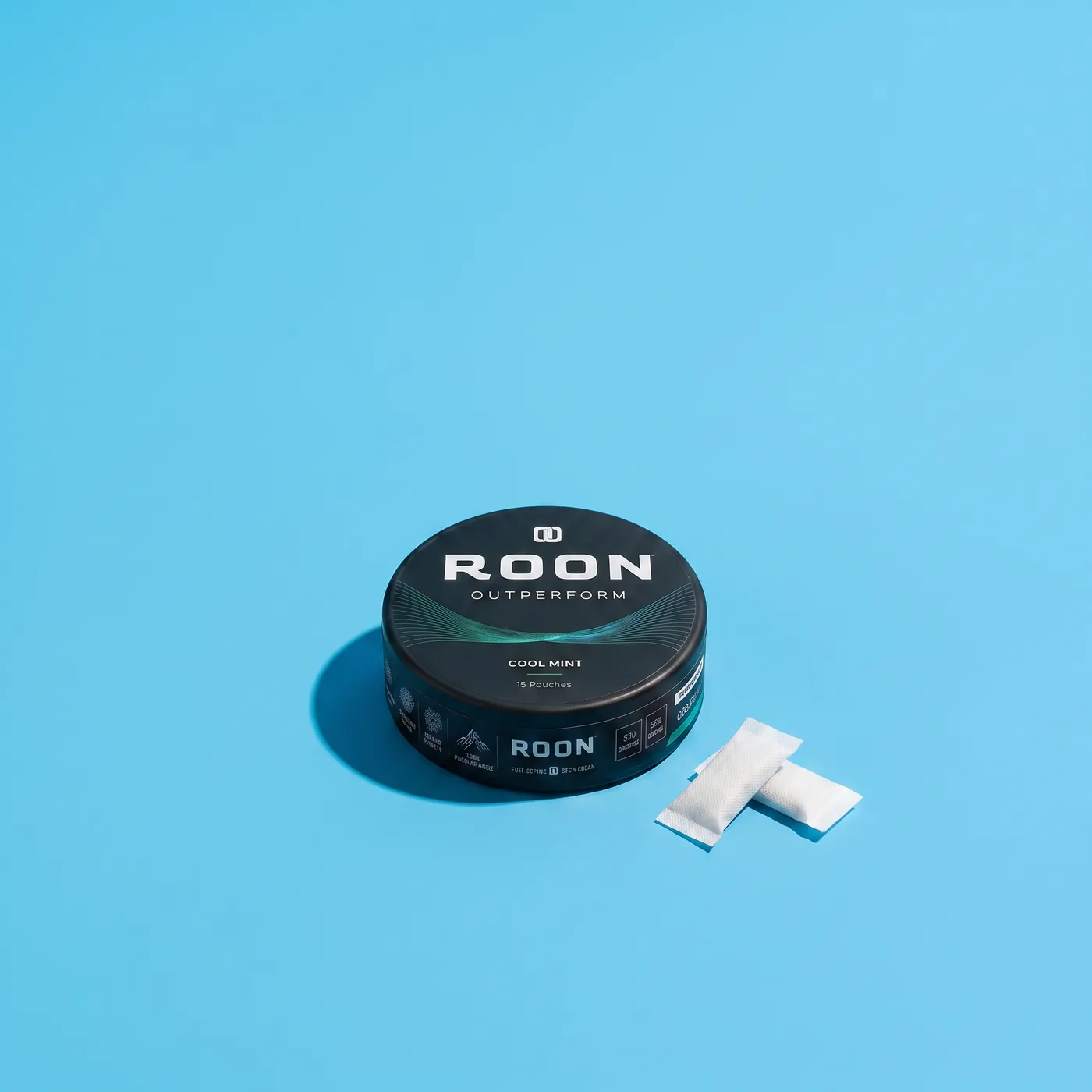 A closed tin of Roon Cool Mint pouches on an aircraft tray table in bright cabin daylight.