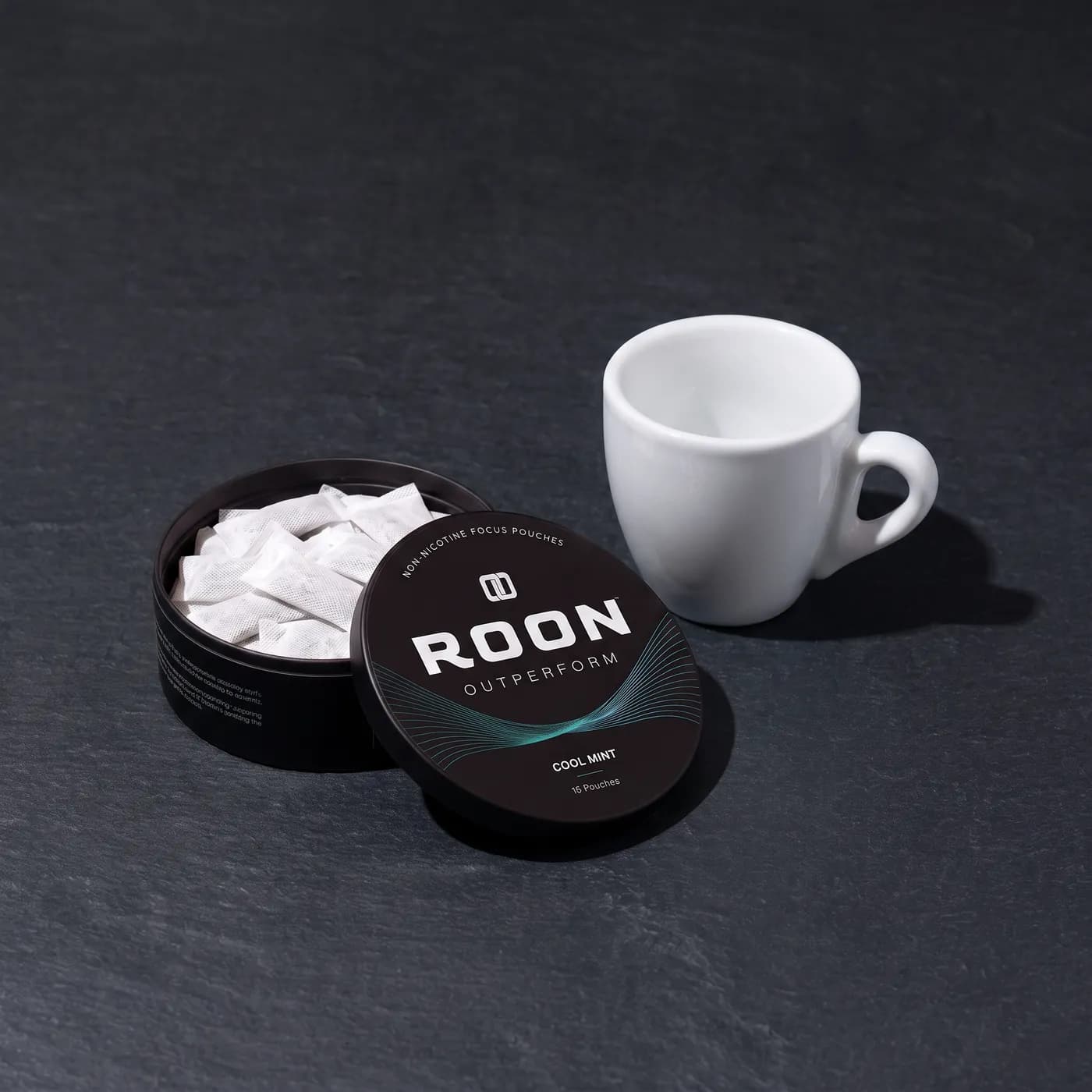 An open tin of Roon Cool Mint pouches beside an empty espresso cup, comparing a pouch to a cup of coffee.