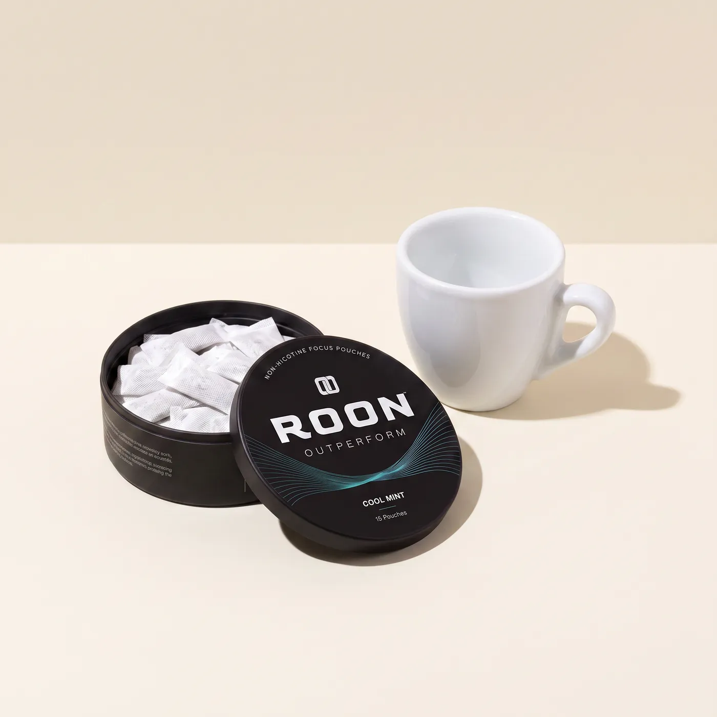 An open tin of Roon Cool Mint pouches beside an empty espresso cup, comparing a pouch to a cup of coffee.