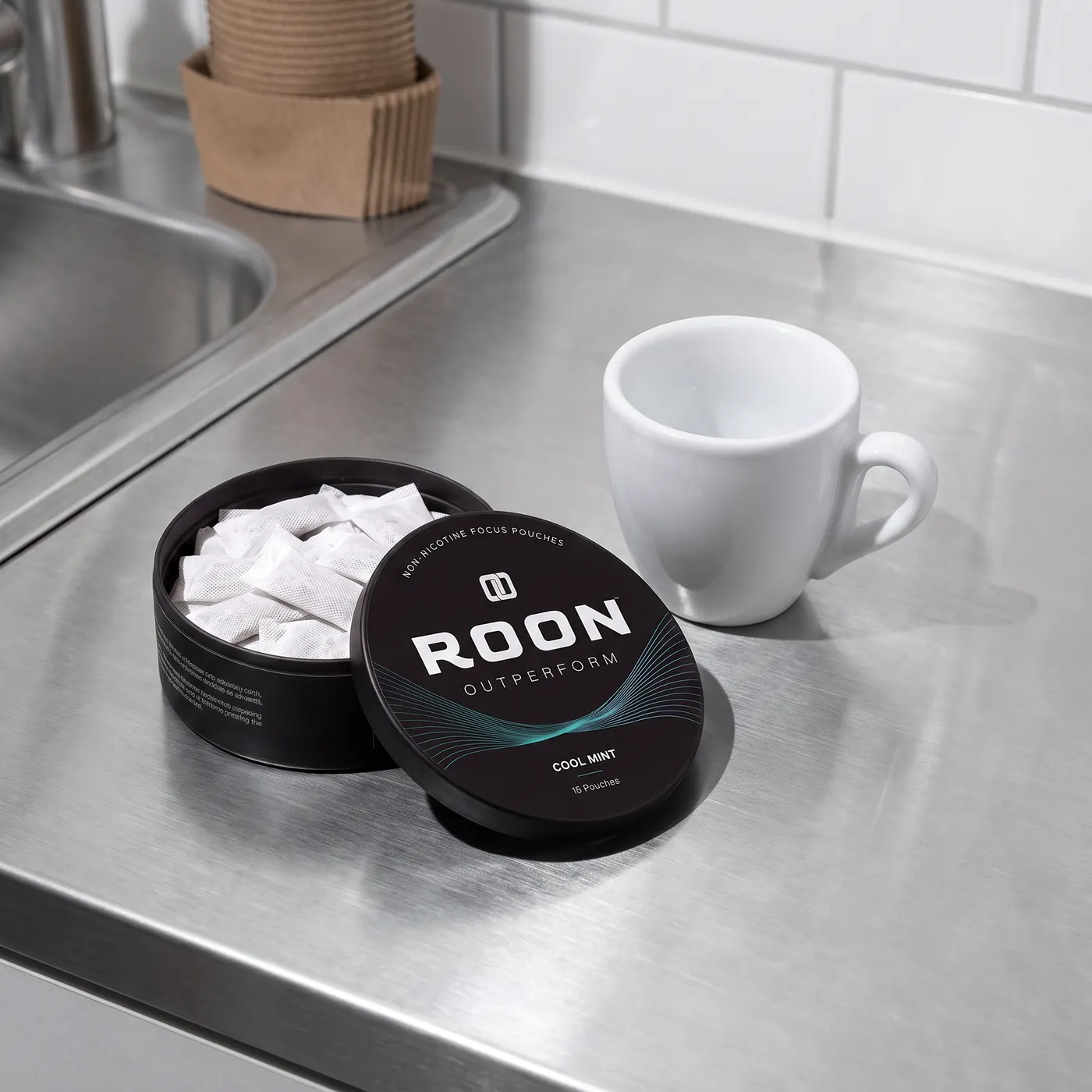An open tin of Roon Cool Mint pouches beside an empty espresso cup, comparing a pouch to a cup of coffee.